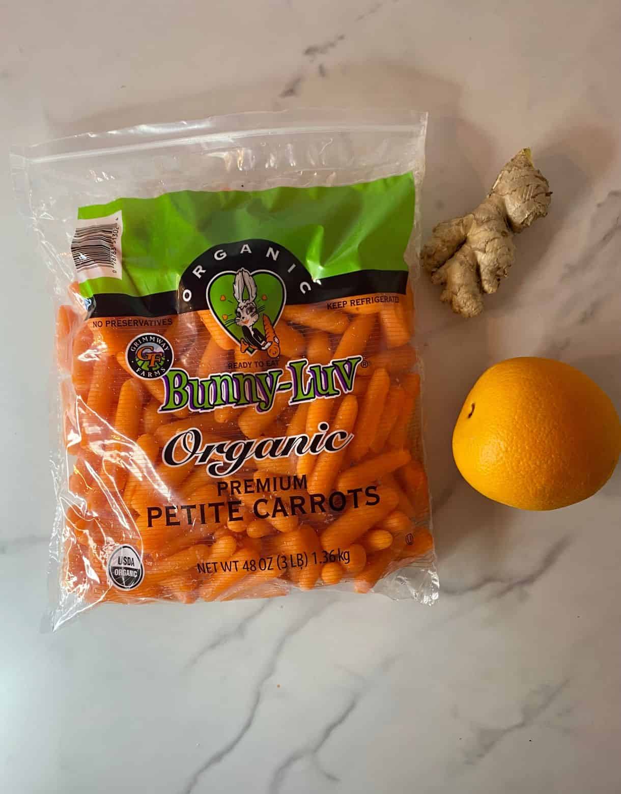 A bag of carrots, a knob of ginger and an orange.