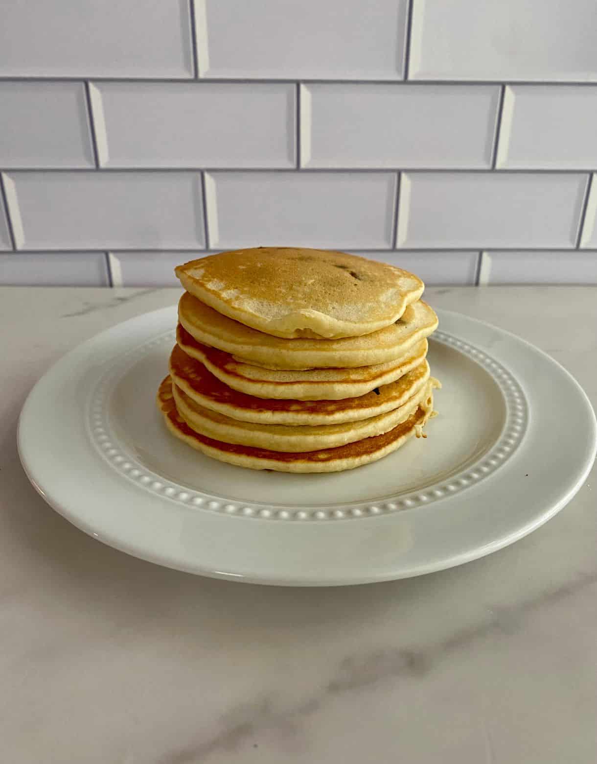 A plate with a stack of chocolate chip pancakes.