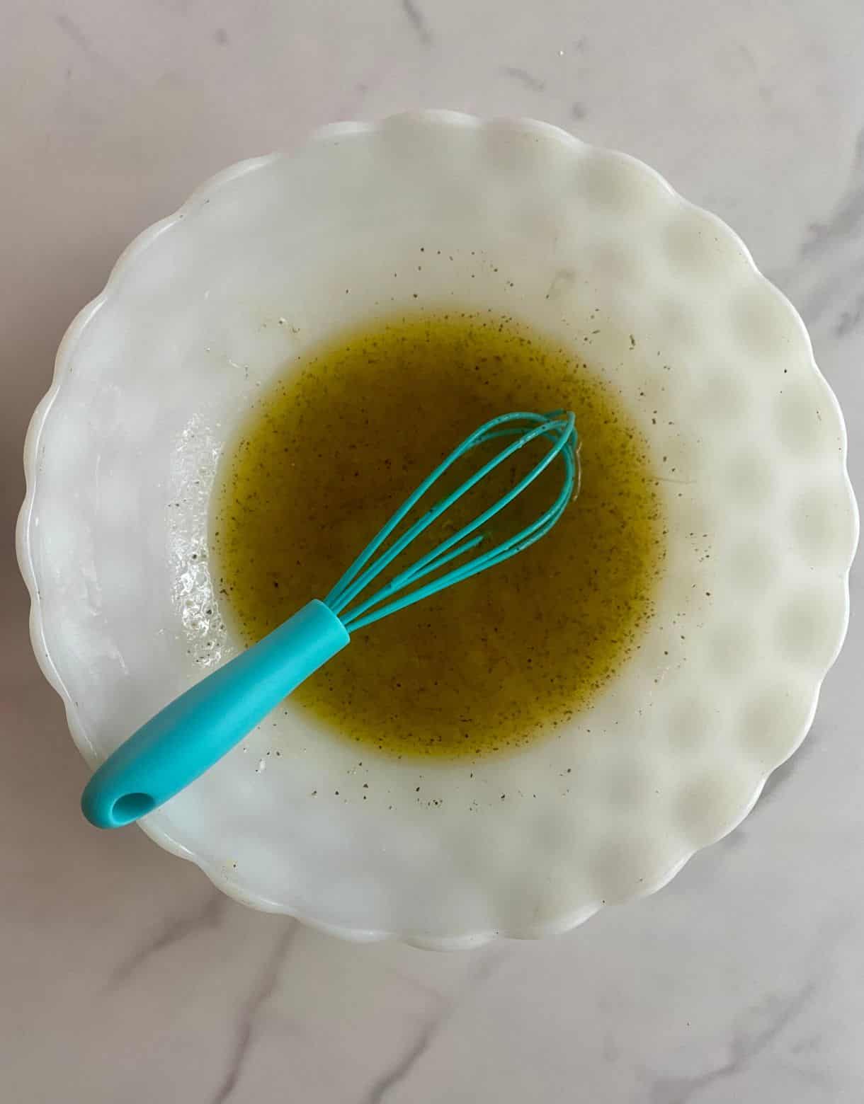 A bowl with dressing for Chopped Greek Salad.