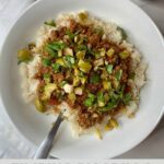 A bowl of Filipino Picadillo with cauliflower rice and spiced meat topped with chopped olives and cilantro with the Healthy Mom Healthy Family logo.