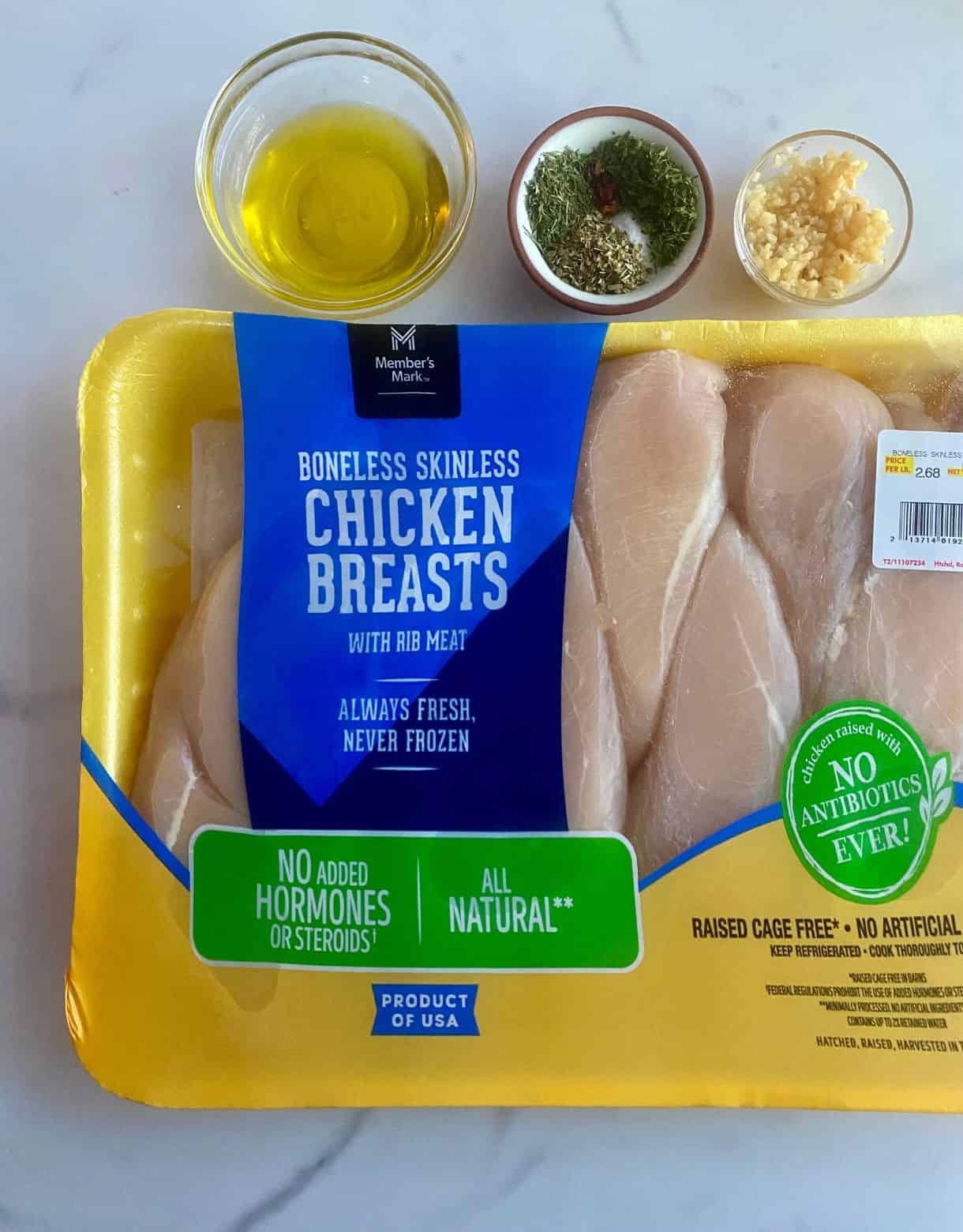 Ingredients for Mediterranean Chicken Tray Bake. Olive oil, spices, garlic and raw chicken breasts.