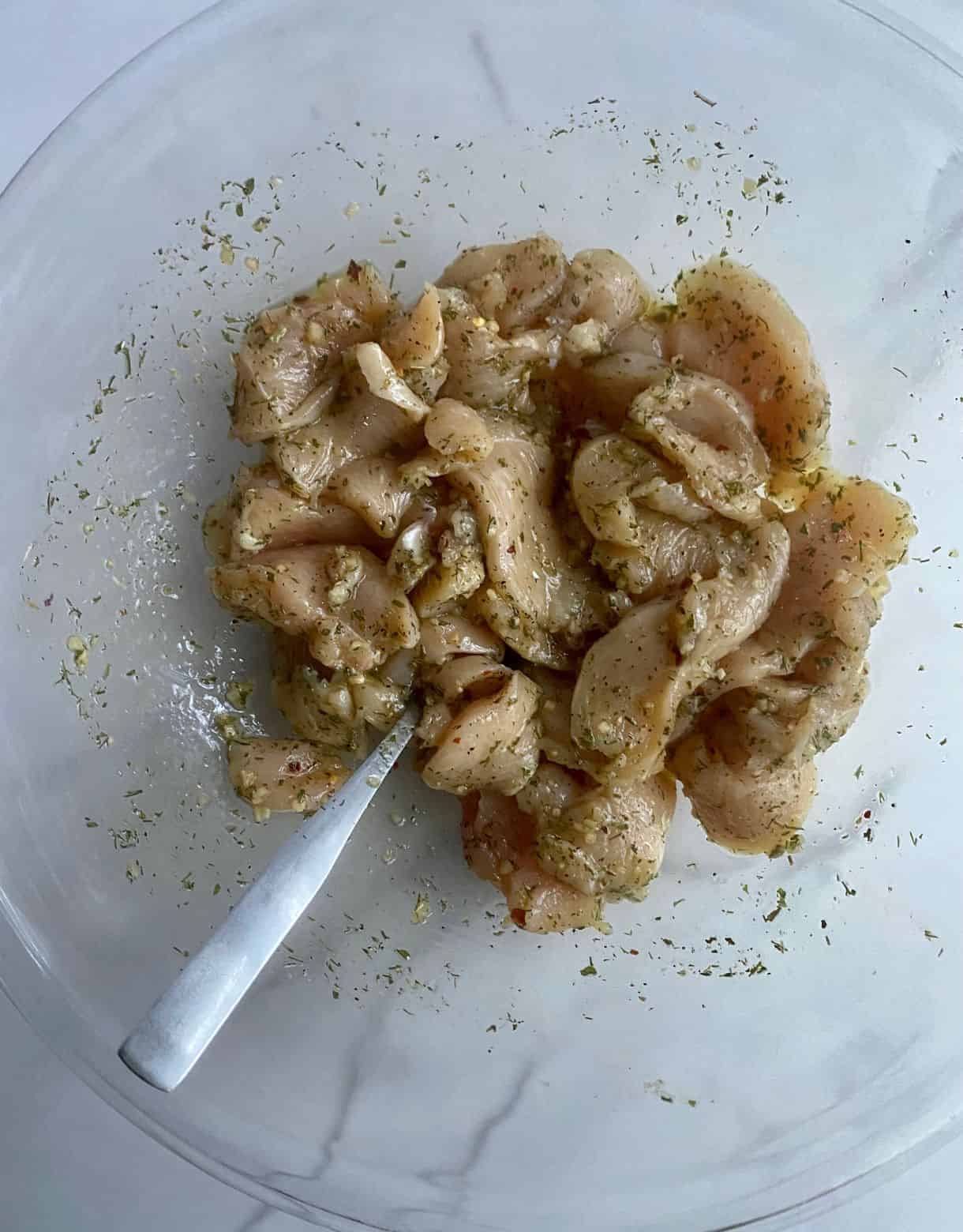 Bowl with seasoned raw Mediterranean Chicken.