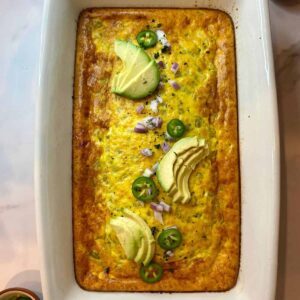 Green Chile Egg Casserole in a pan with sliced avocado on top.
