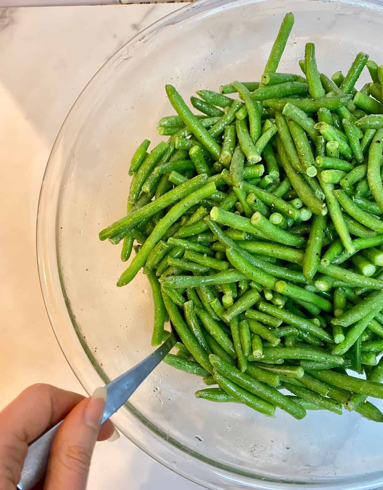 A bowl of frozen green beans tossed in oil.