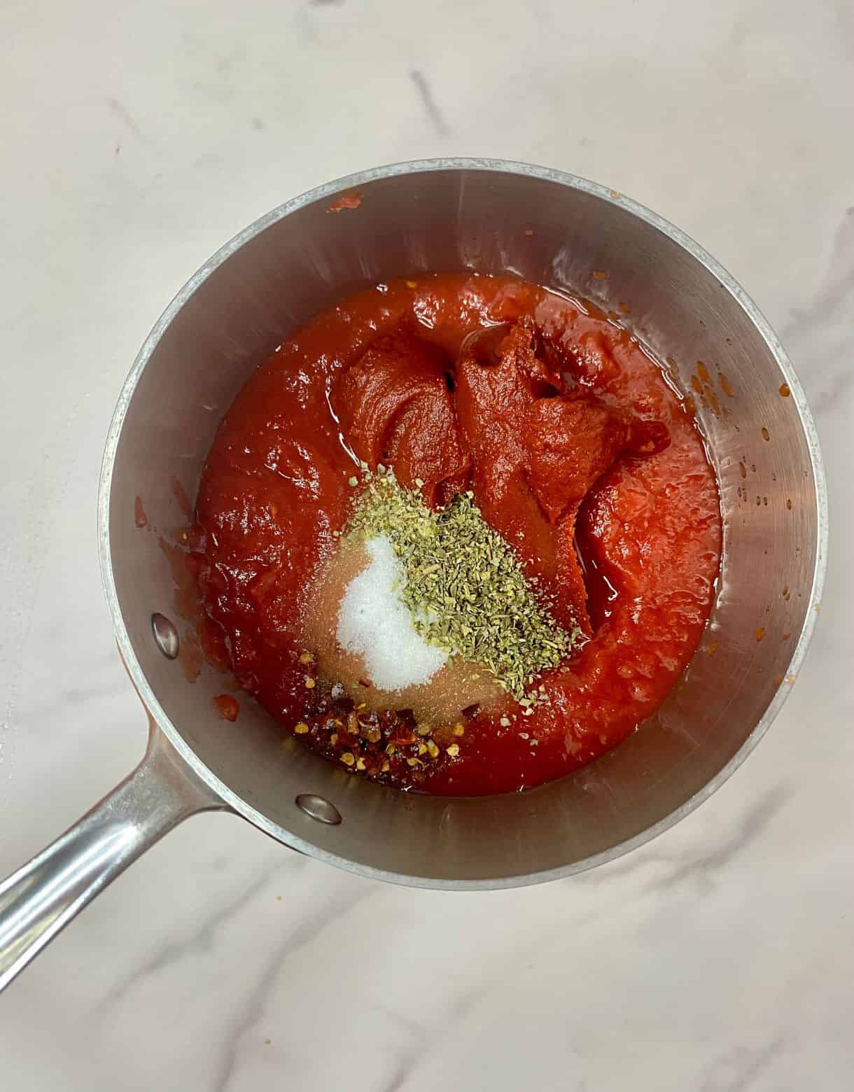 A small pot with ingredients for Easy Marinara Sauce added but not stirred.