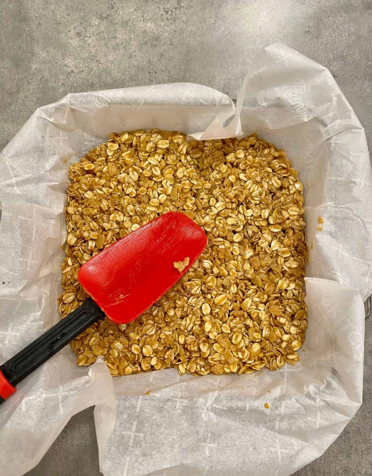 A pan of No-Bake Peanut Butter Granola bars, with a spoon before they are cut.