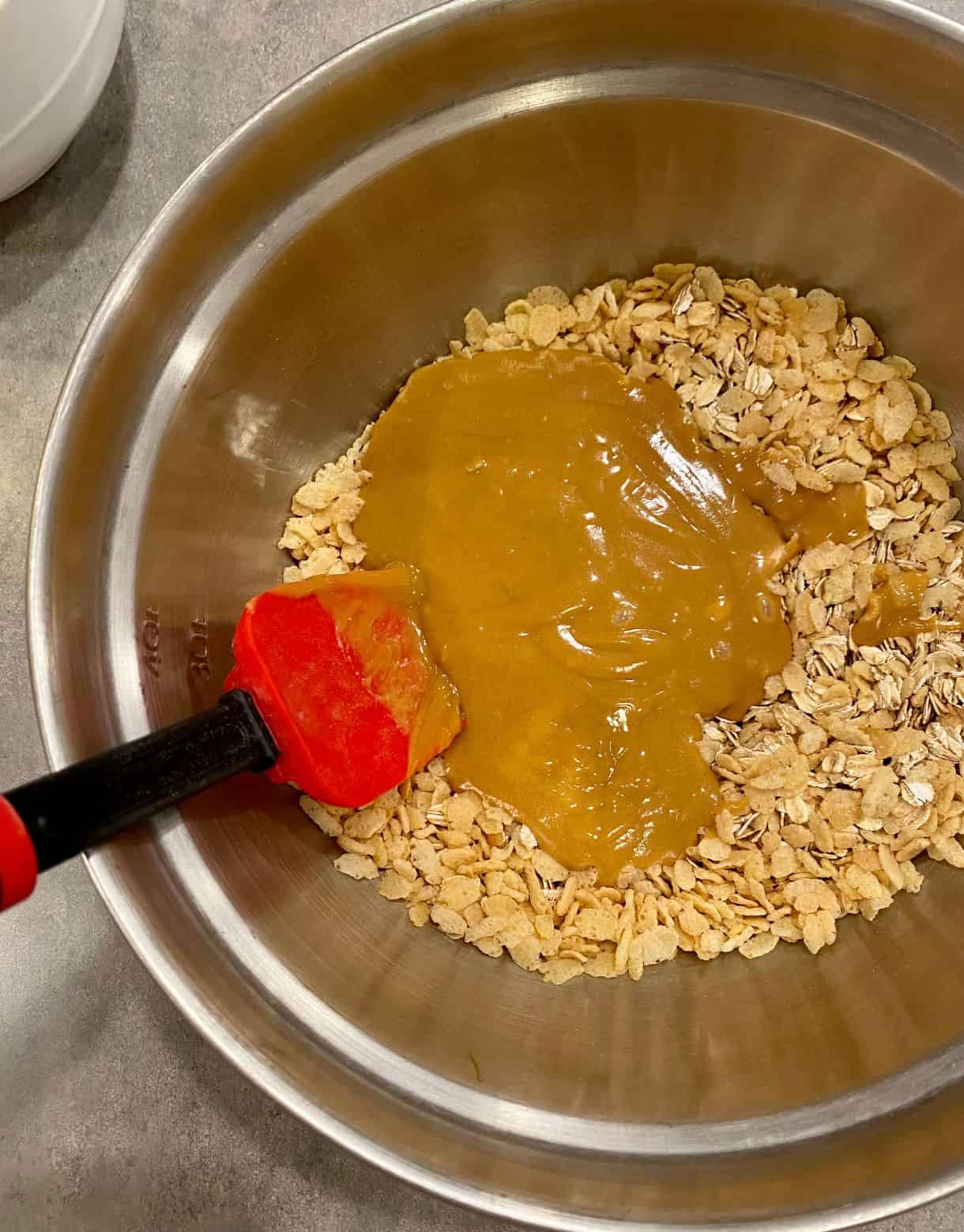 A mixing bowl containing ingredients for No-Bake Peanut Butter Granola Bars with a spoon.