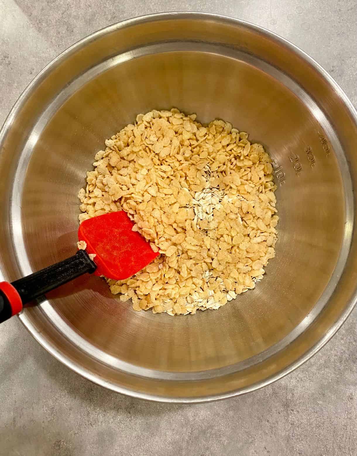 A mixing bowl with crispy rice cereal, oats and salt.