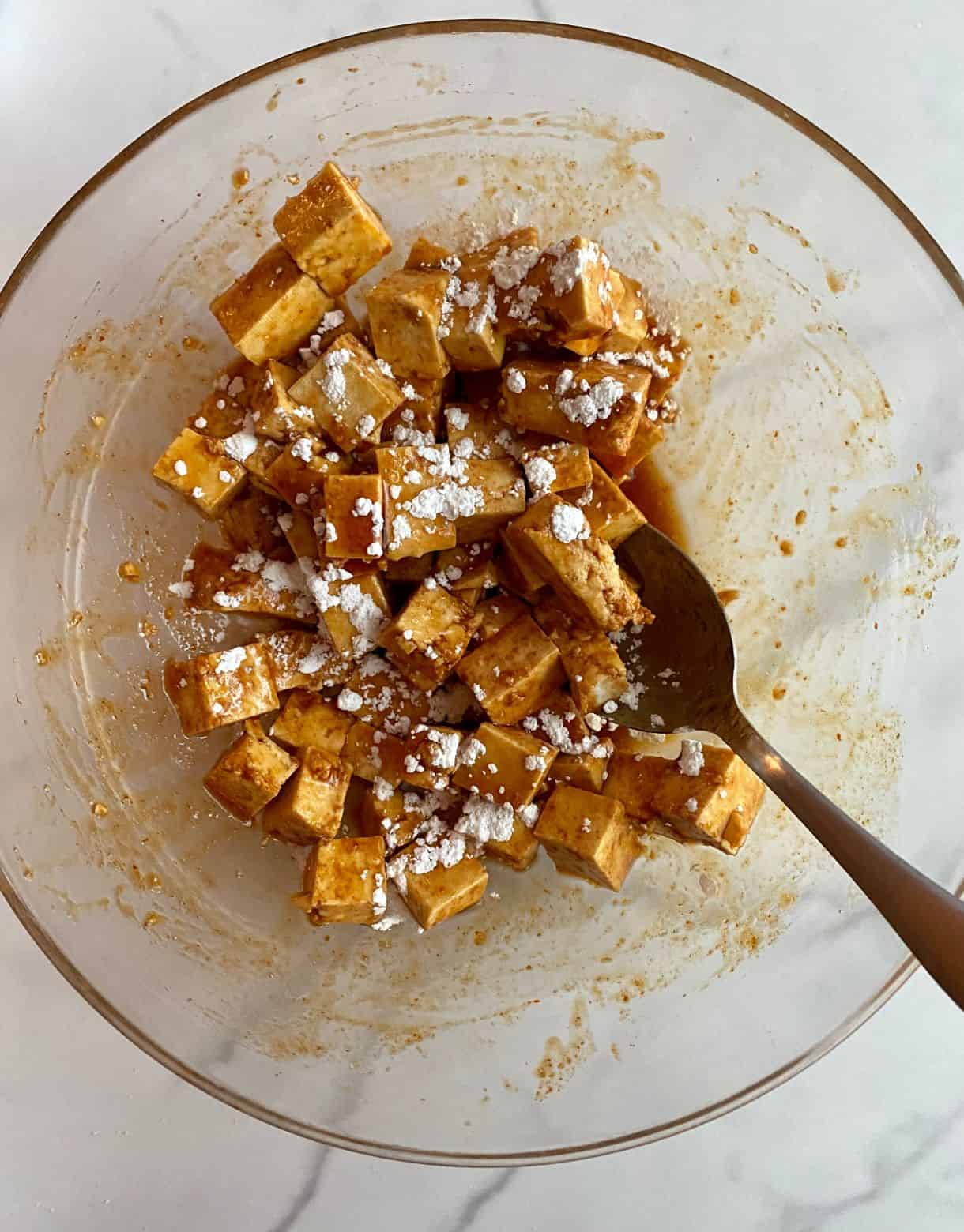 A bowl of marinated Sesame Tofu sprinkled with cornstarch.
