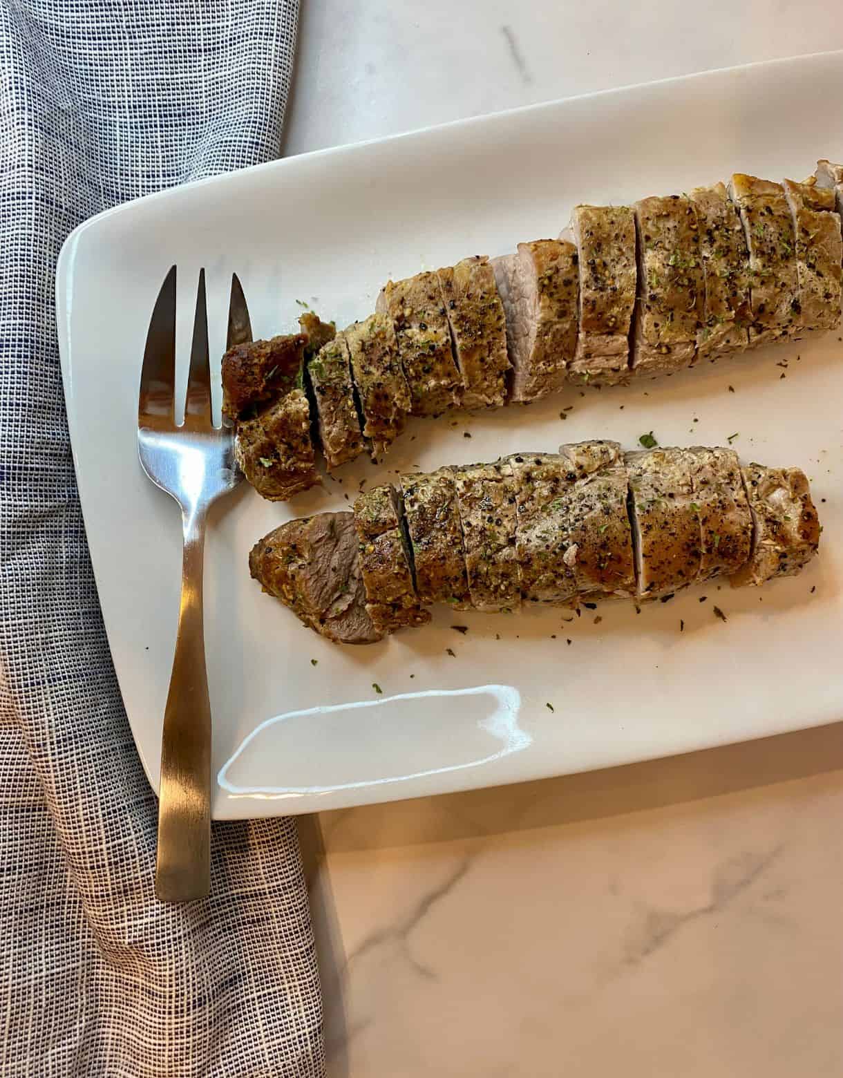 Two cooked and sliced pork tenderloins on a platter.
