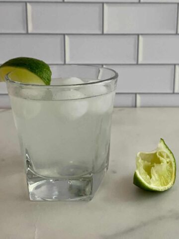 A glass of Skinny Cocktail with ice and a lime wedge.
