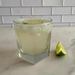 A Coconut Water Cocktail in a glass with a wedge of lime.