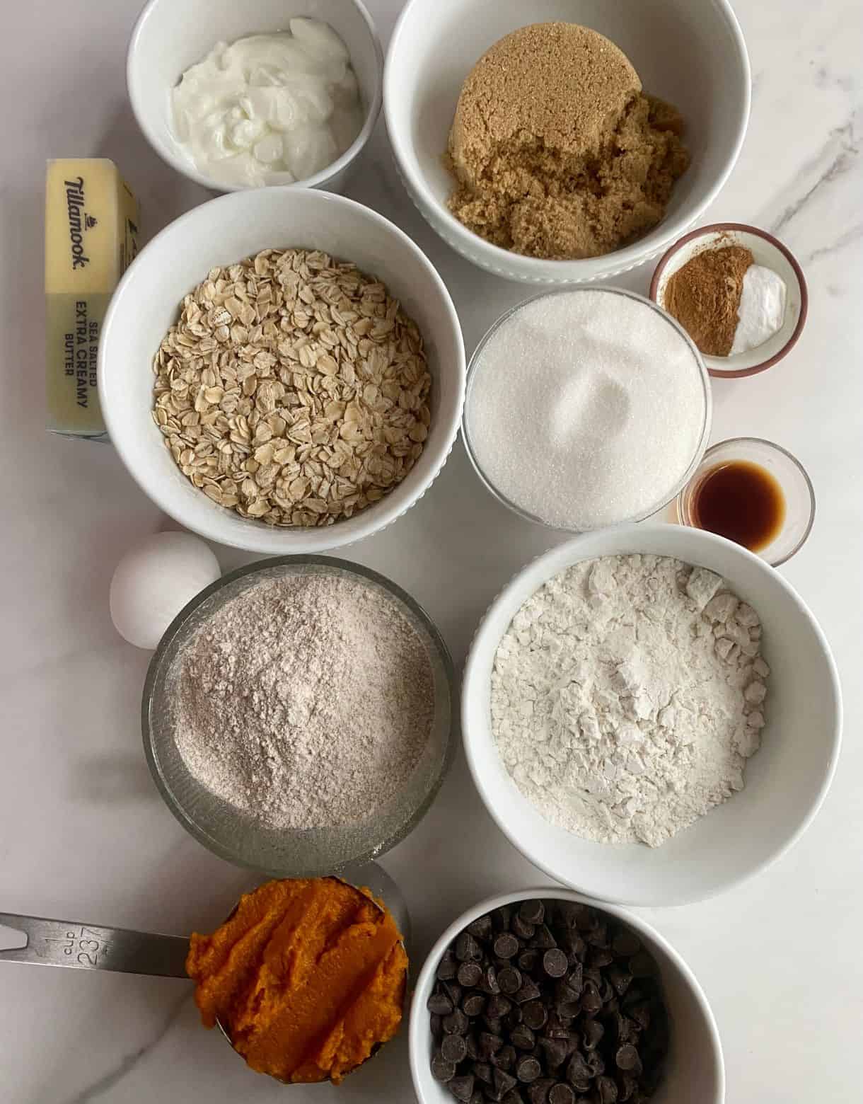 Yogurt, brown sugar, butter, rolled oats, sugar, cinnamon, baking soda, an egg, vanilla extract, whole wheat flour, all-purpose flour, pumpkin puree and chocolate chips.