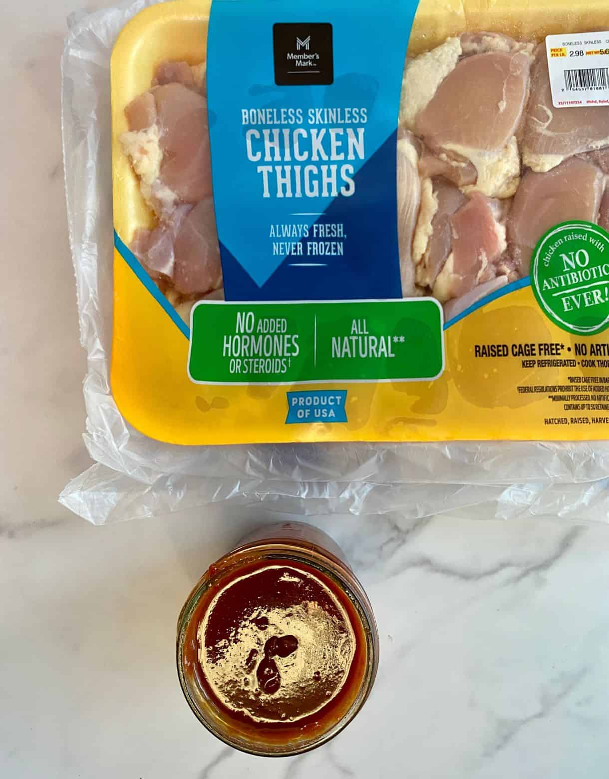 A pack of chicken thighs and a dish of BBQ sauce.