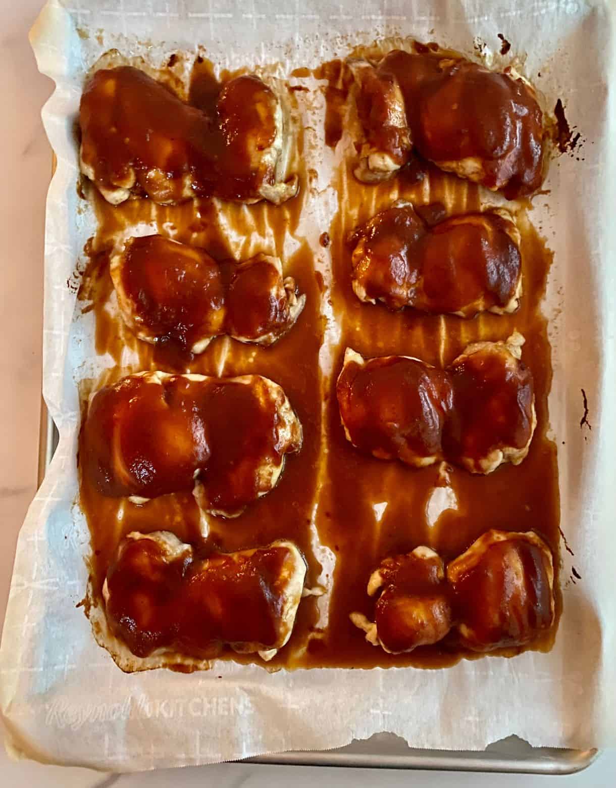 A sheet pan with cooked BBQ Chicken Thighs.