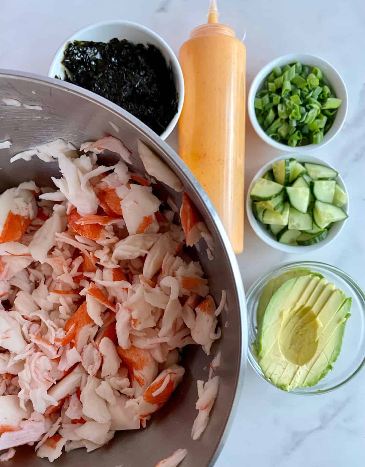 Crab, chopped seaweed, a bottle of Sriracha Mayo, sliced scallions, diced cucumbers and sliced avocado for Deconstructed Sushi Bowls.