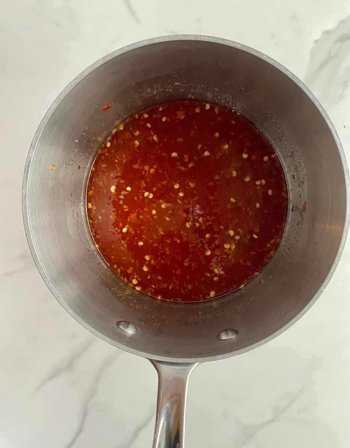 A pot with the ingredients for sweet chili sauce mixed in it.
