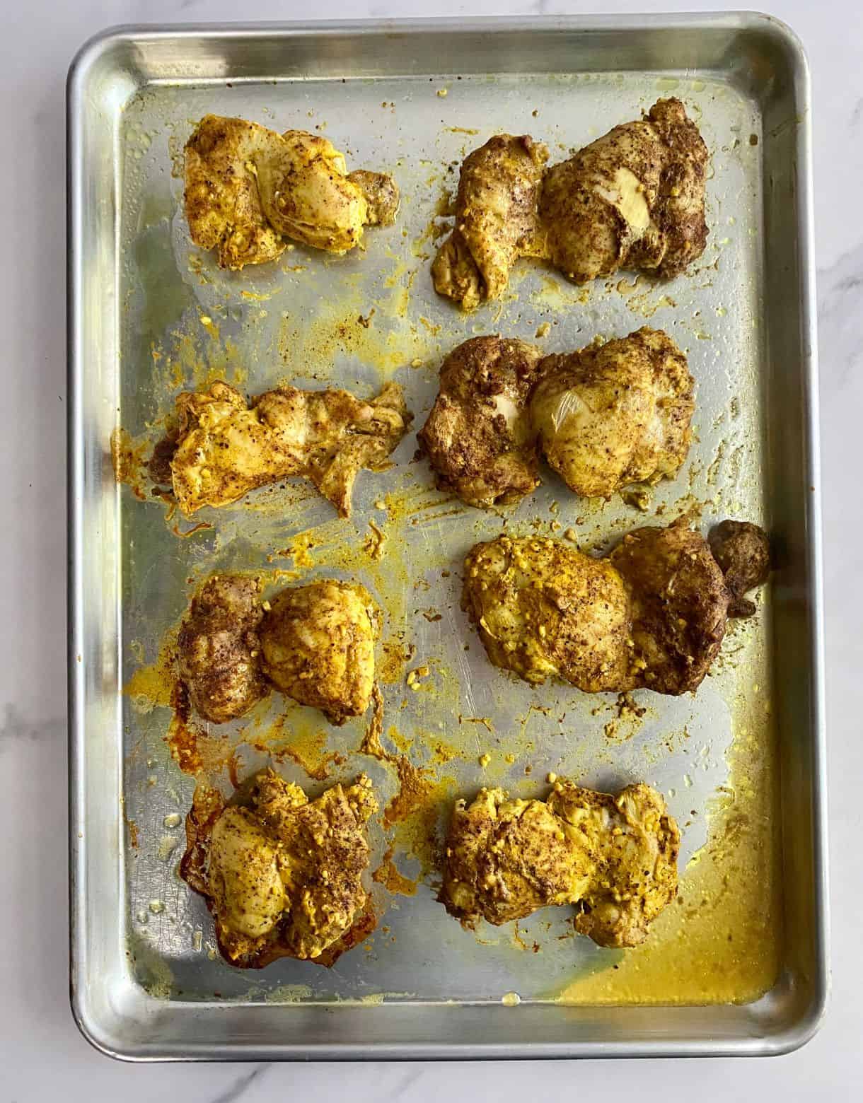A sheet pan with cooked chicken thighs.