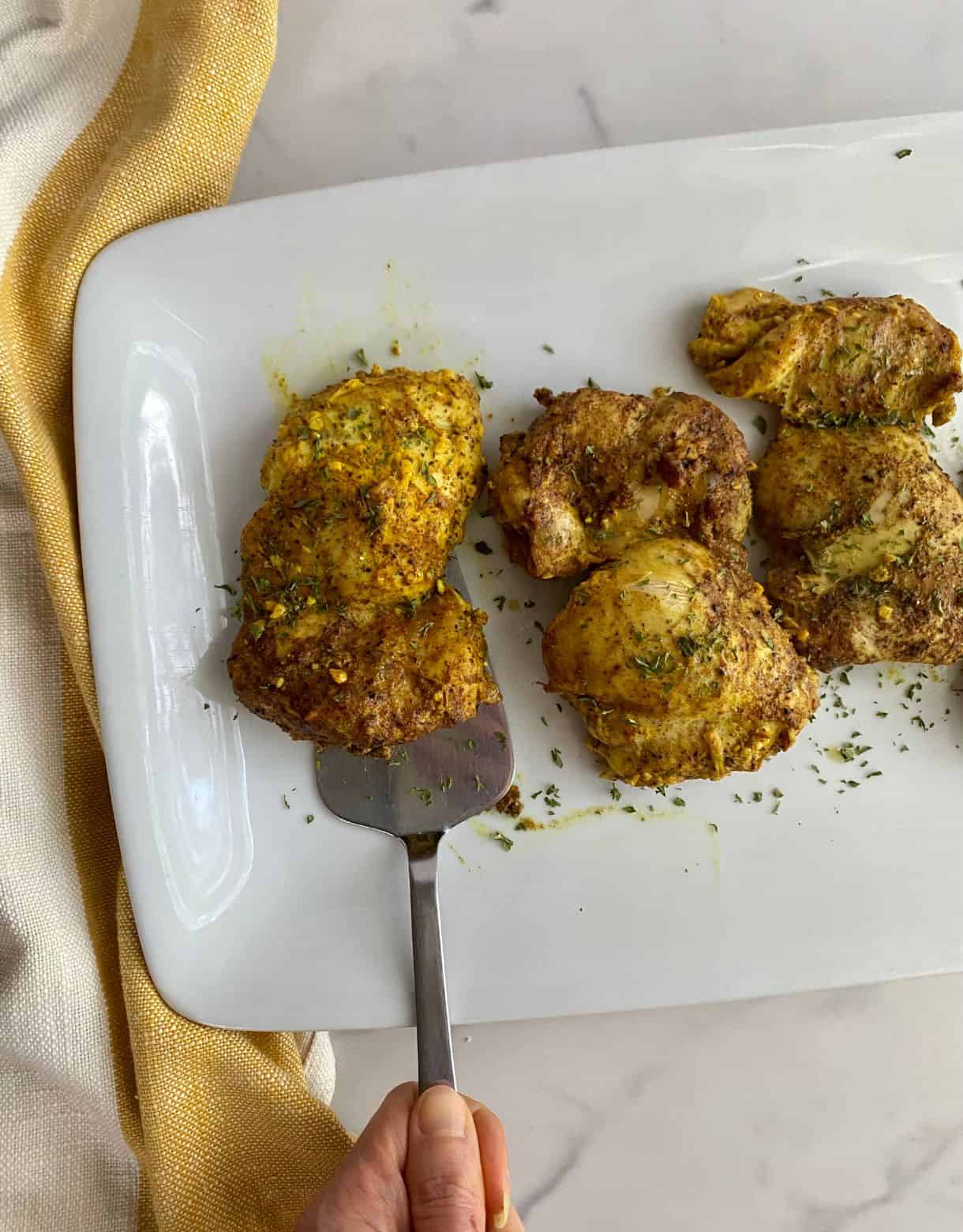 A platter with 3 cooked Garam Masala Chicken Thighs.
