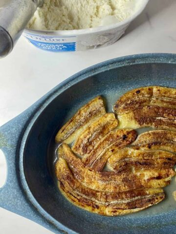 A dish with baked Healthy Bananas Foster and a tub of vanilla ice cream with a scoop in it.