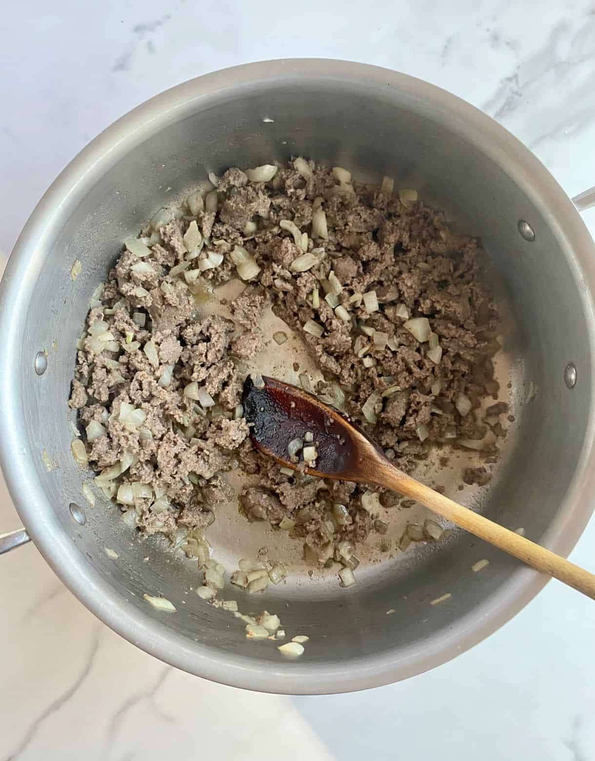 A pot with cooked turkey sausage and onion.