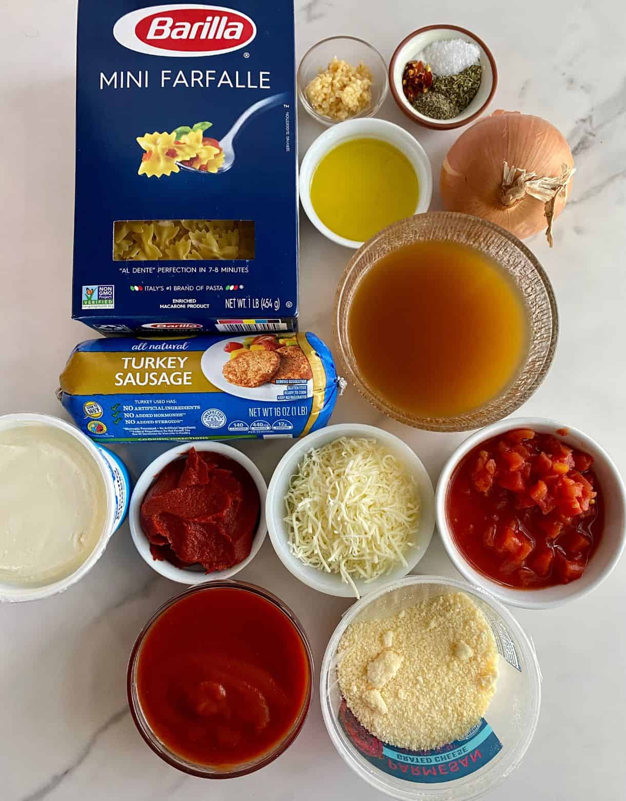 Bow tie pasta, garlic, salt, pepper, sugar, Italian seasoning, red pepper flakes, olive oil, onion, chicken broth, turkey sausage, ricotta cheese, tomato paste, mozzarella cheese, diced tomatoes, tomato sauce and parmesan cheese.