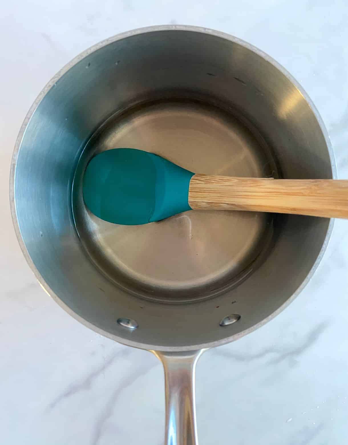A small pot with white vinegar with salt and sugar dissolved into it and a spoon.