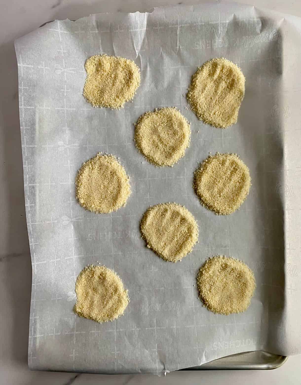 A sheet pan lined with parchment with Baked Cheese Chips ready to go in th oven.
