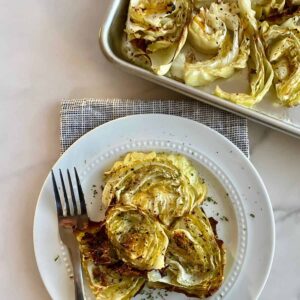 A plate with cooked Oven Roasted Cabbage Steaks and a fork.