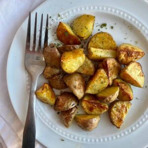 A plate of cooked Roasted Mini Potatoes with a fork.