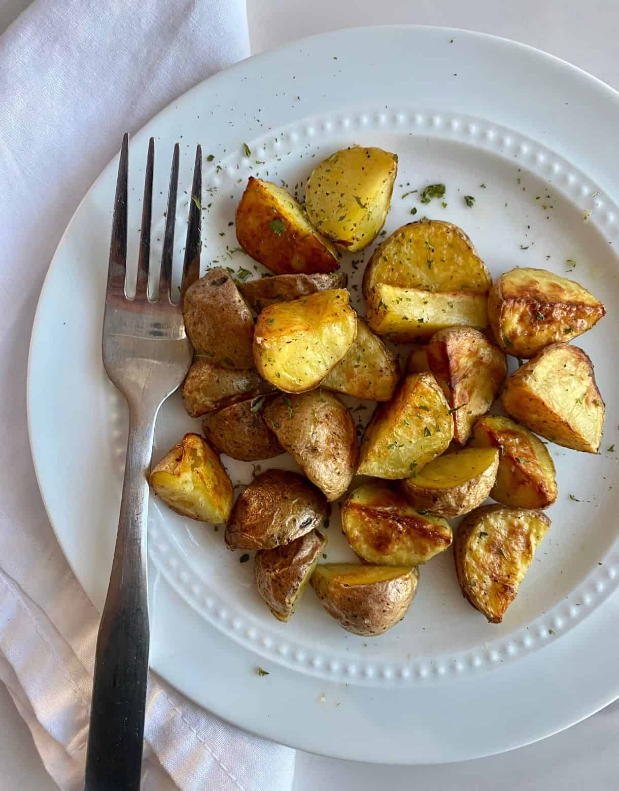 A plate of cooked Roasted Baby Potatoes with a fork.