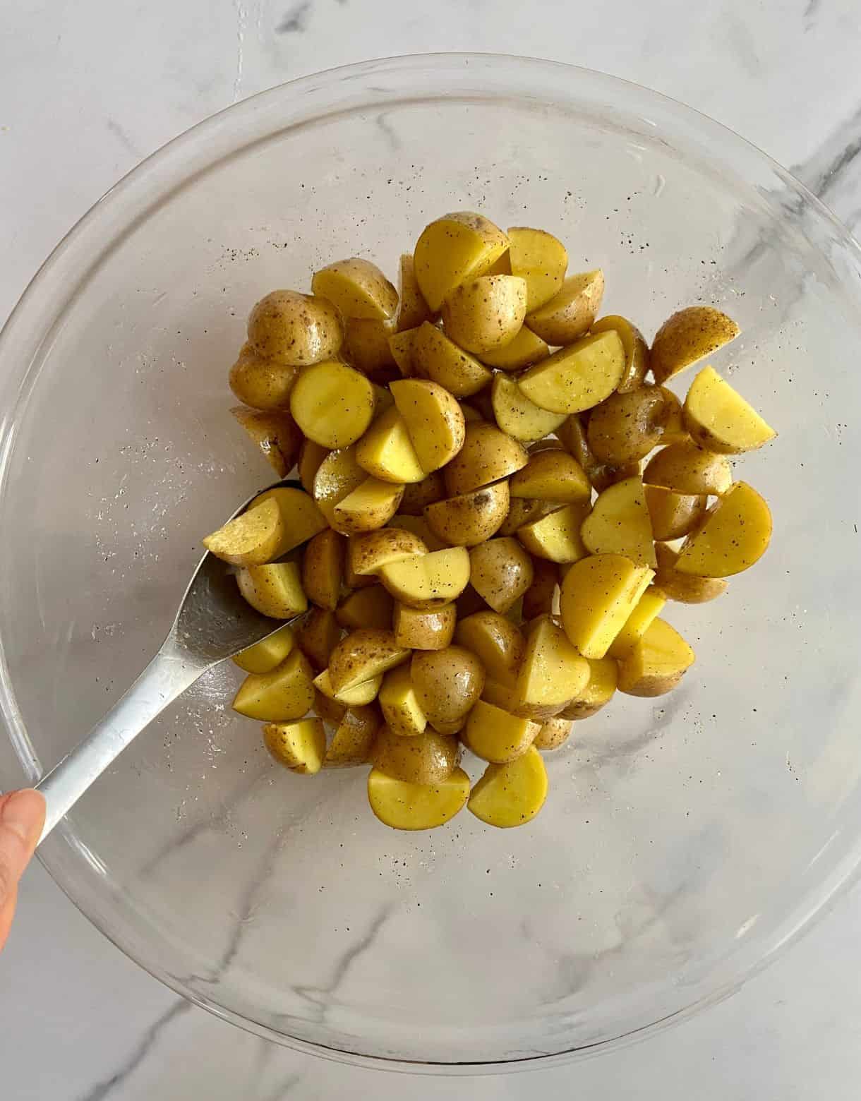 A bowl with diced mini potatoes and a spoon.
