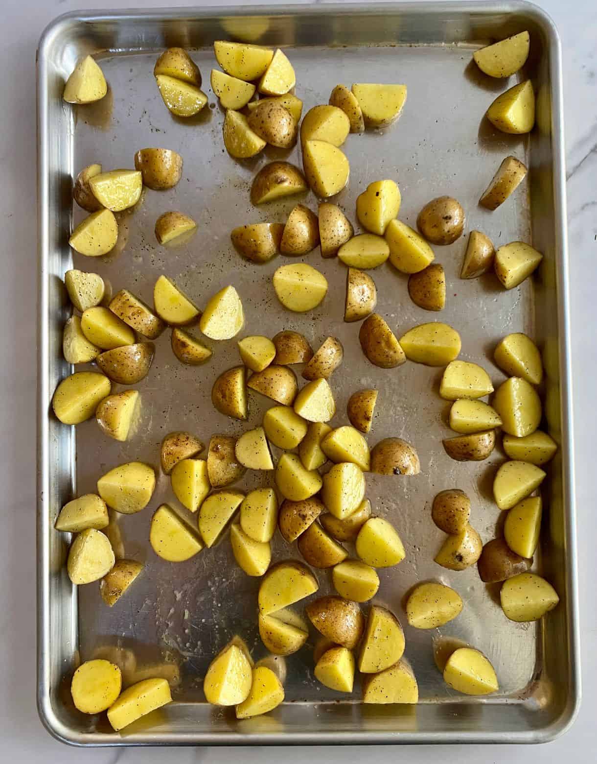 A sheet pan with raw diced potatoes.