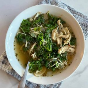 A bowl of Chicken Kale Soup with a spoon.