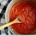 A pot of Spicy Marinara Sauce with a wooden spoon in it and the Healthy Mom Healthy Family logo.