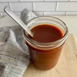 A jar of Sweet and Spicy BBQ Sauce with a spoon.
