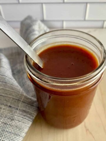 A jar of Sweet and Spicy BBQ Sauce with a spoon.