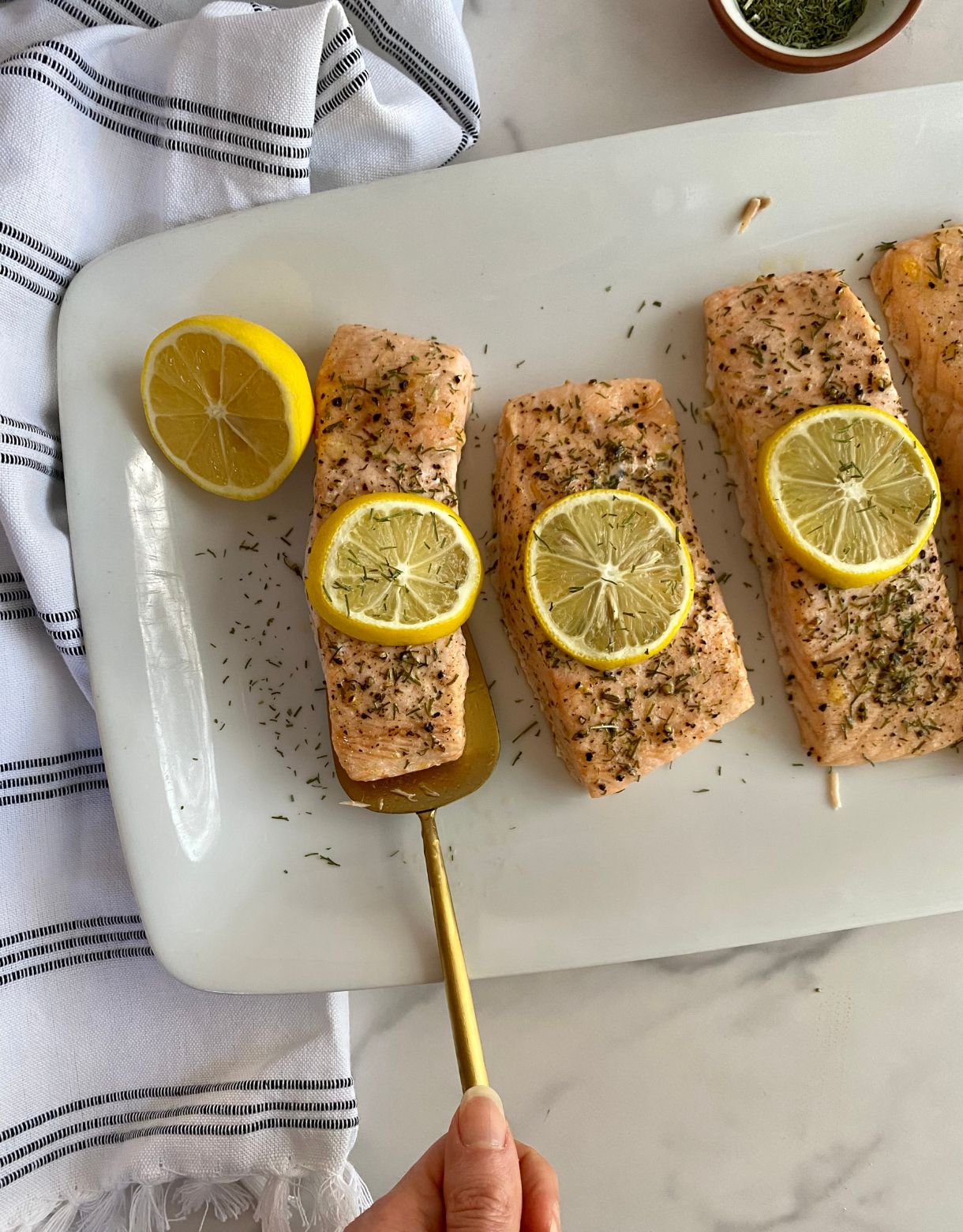 A platter with cooked Baked Salmon with Dill and Lemon.
