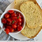 A bowl of Bruschetta Dip with a spoon and 3 slices of toasted buttered bread.