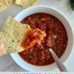 A bowl of Jalapeno Salsa with a spoon and a chip dipped in the salsa.