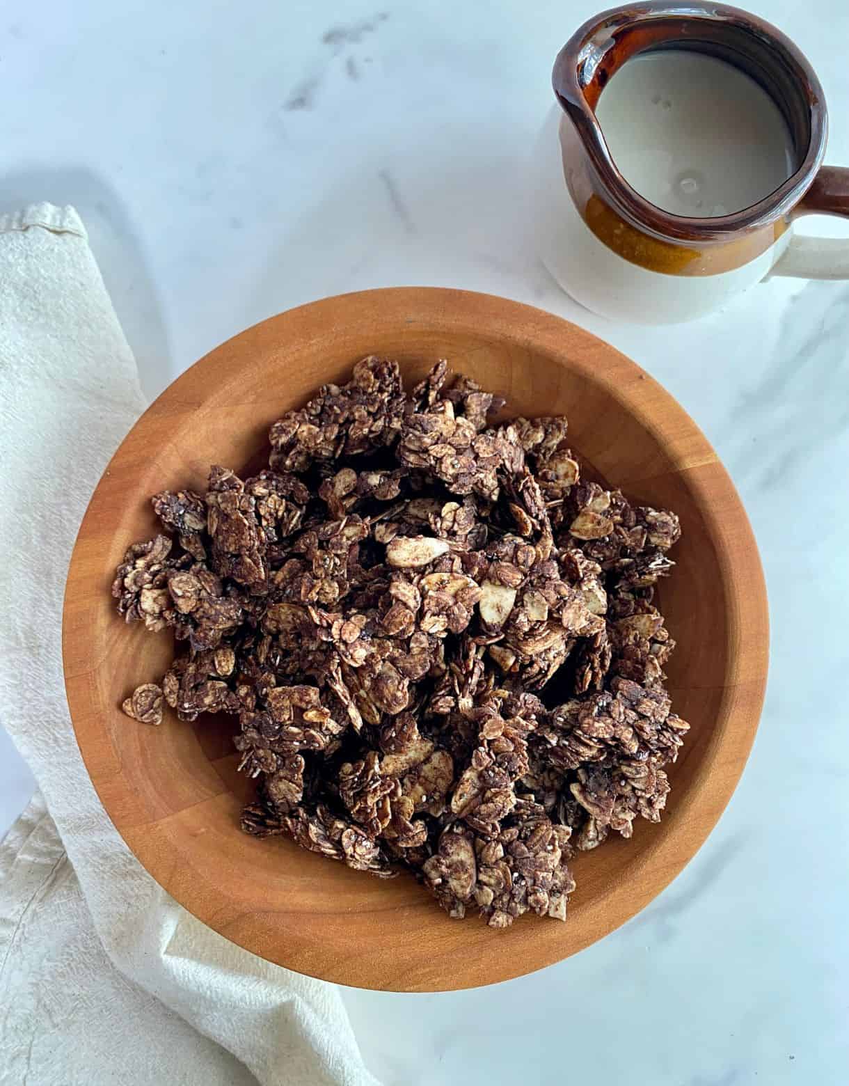A bowl of Dark Chocolate Granola and a pitcher of almond milk.