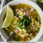 A bowl of Green Chile Chicken Soup with a spoon and a wedge of lime.