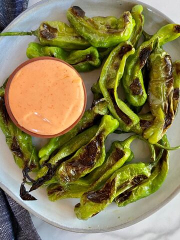 A plate of Grilled Shishito Peppers with Sriracha Mayo dipping sauce.