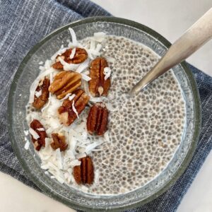 A bowl of Keto Chia Pudding topped with nuts and shredded coconut.