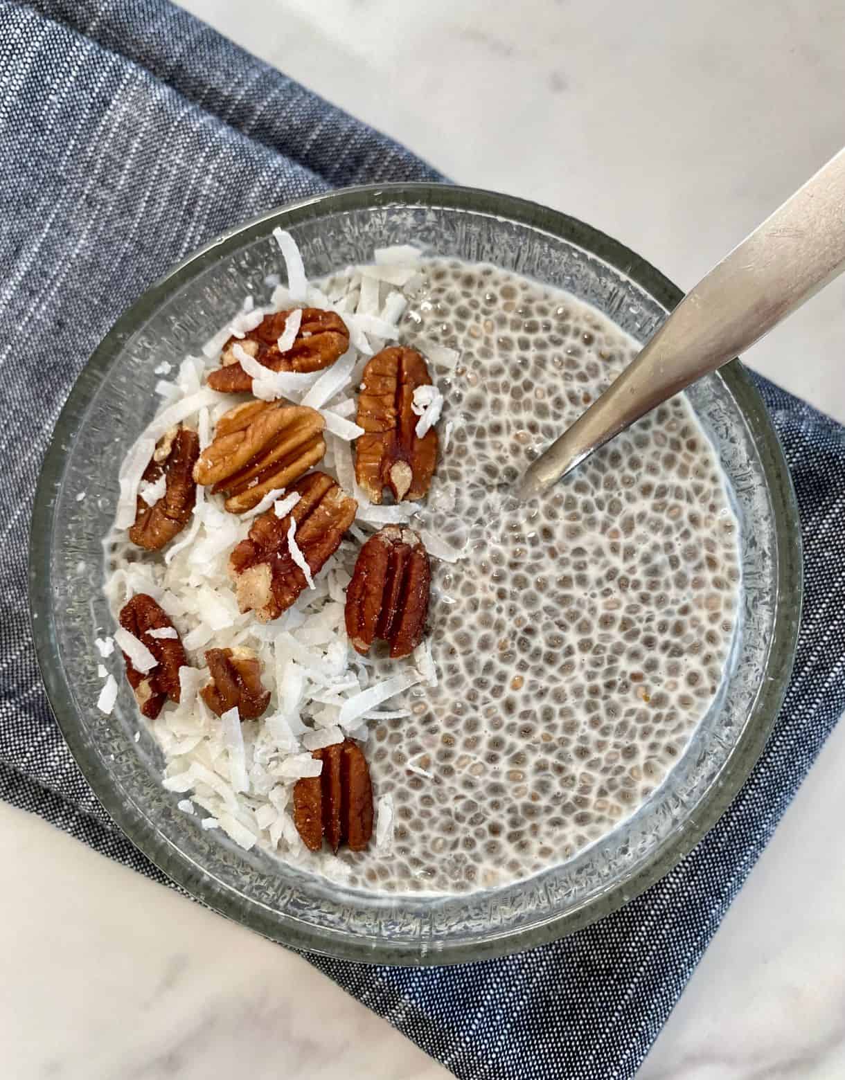 A bowl of Keto Chia Pudding topped with nuts and shredded coconut.