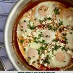 A pot with cooked Turkish Shakshuka topped with feta cheese and cilantro.