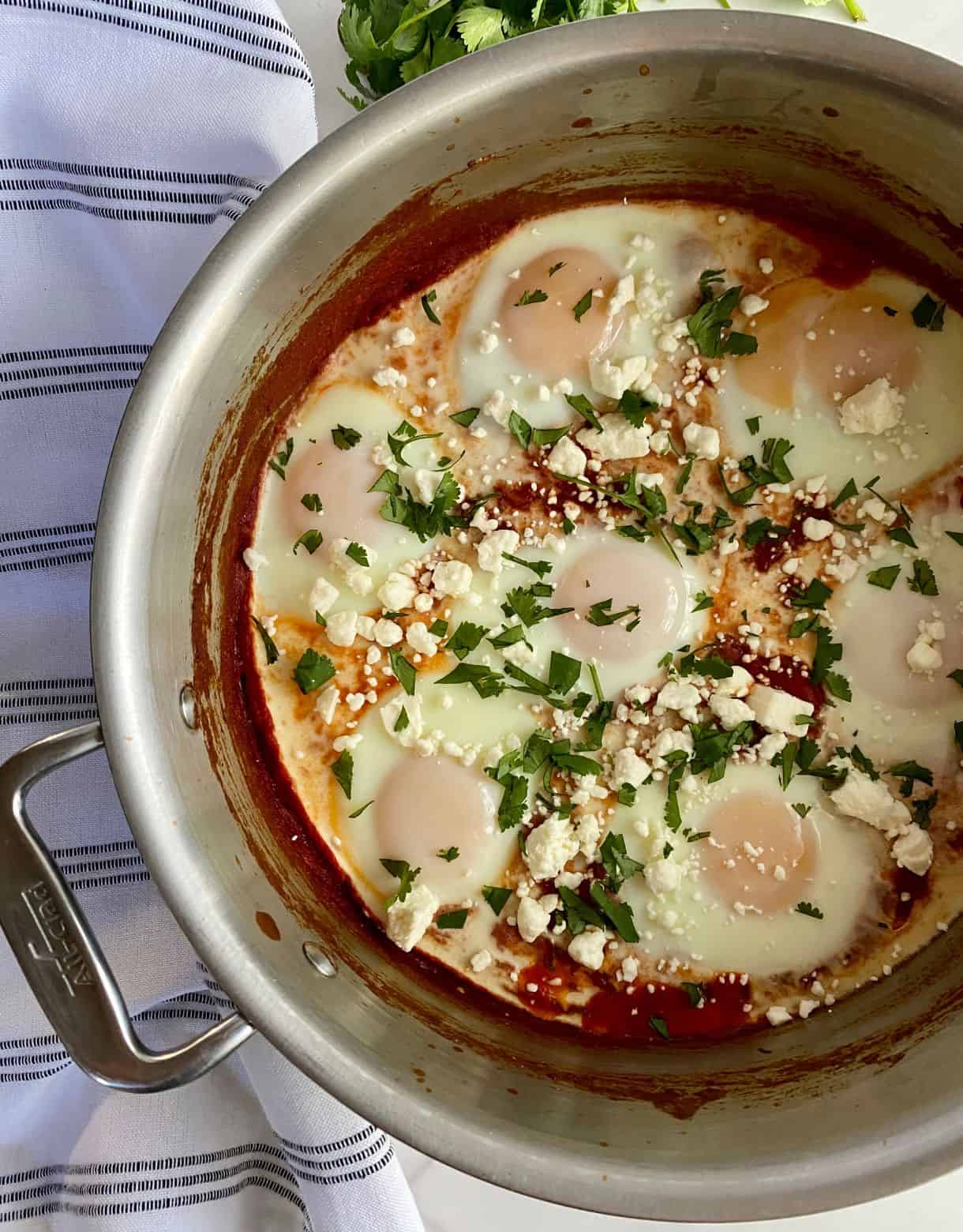 A pot with cooked Turkish Shakshuka topped with feta cheese and cilantro.