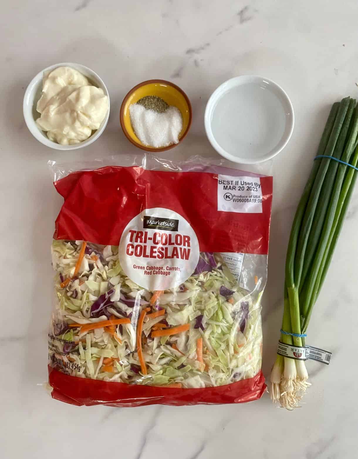 A bag of shredded cole slaw, a bunch of green onions, vinegar, mayonnaise, salt and pepper.