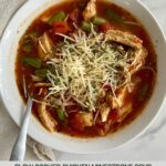 A bowl of cooked Chicken Minestrone Soup topped with parmesan cheese.