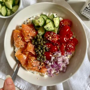 A Savory Cottage Cheese Bowl with cottage cheese, smoked salmon, diced cucmbers, sliced tomatoes, diced red onion, capers and Everything but the Bagel Seasoning.
